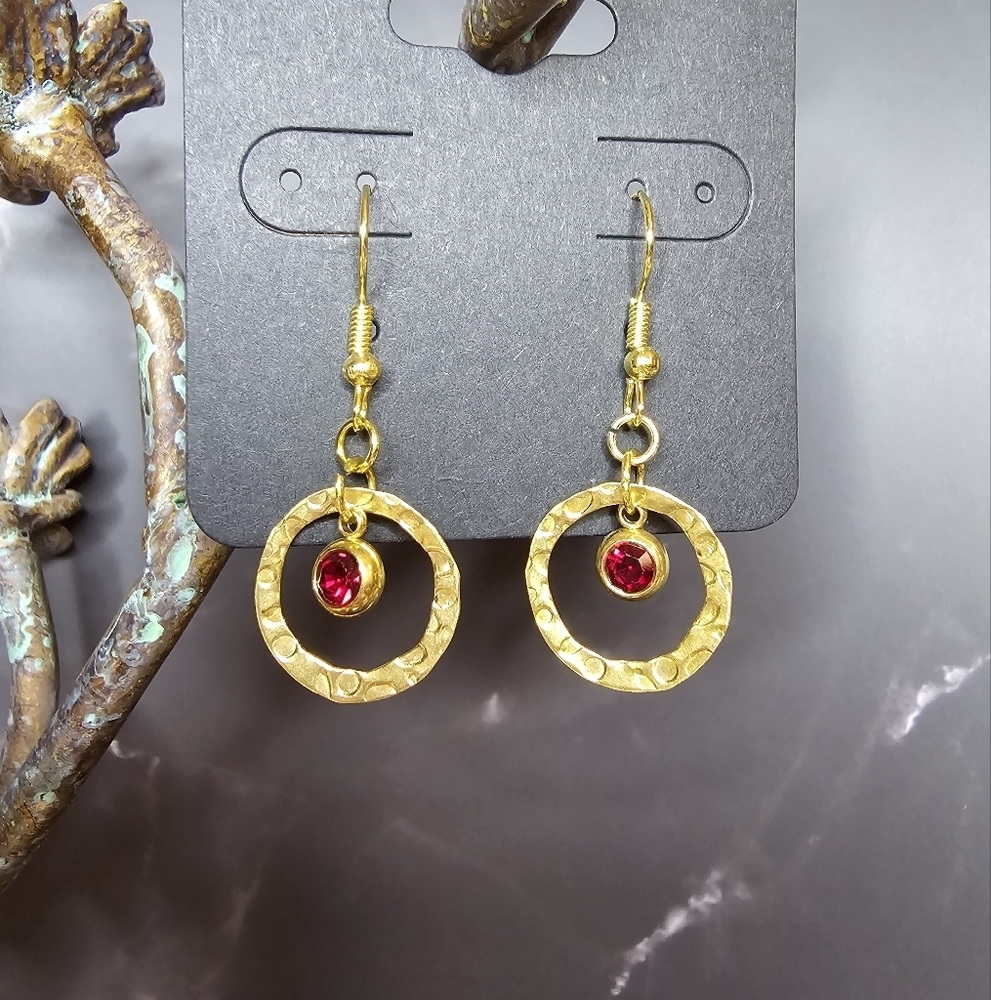 Drop earrings with red rhinestone hanging in brass embossed hollow round disc
